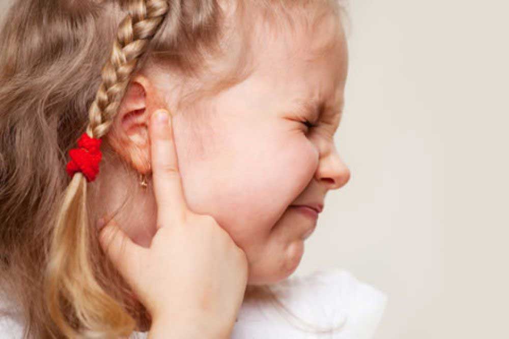 child in pain pointing to ear with infection